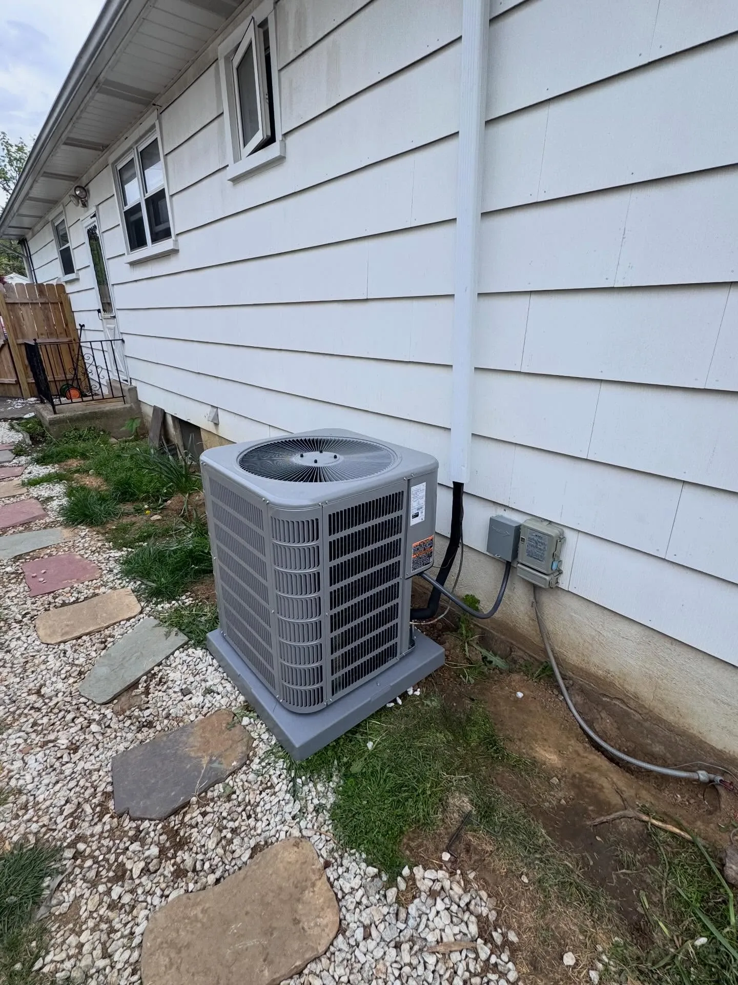 New gray central AC condenser installed beside a South Philadelphia home