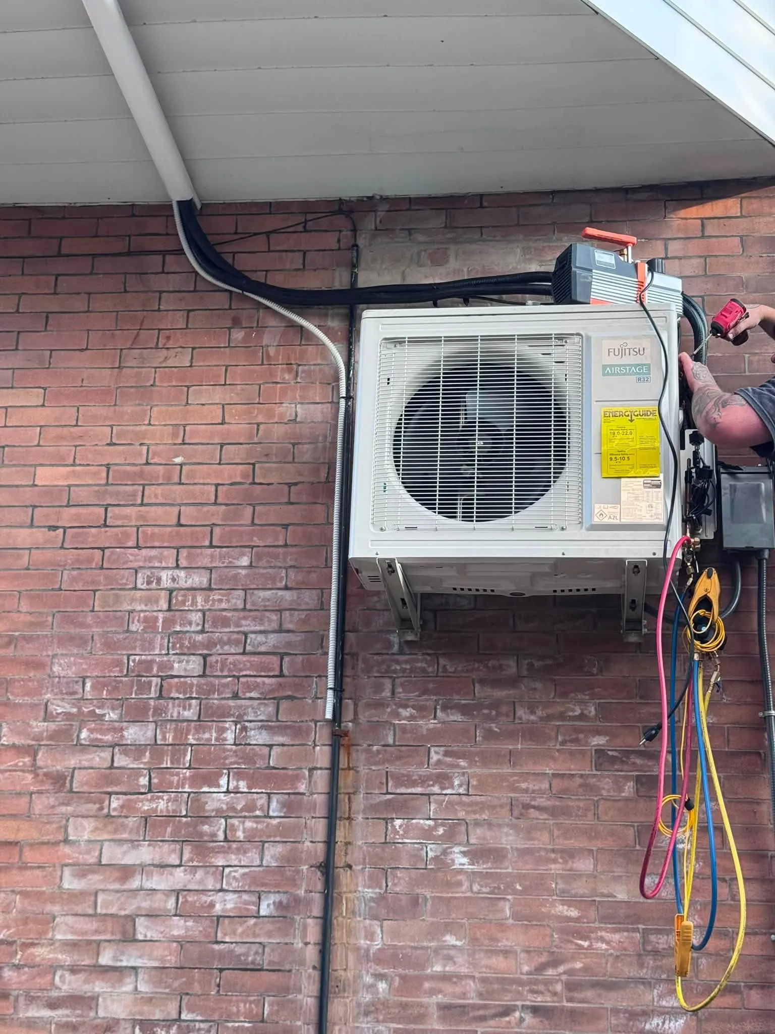 A technician installing a ductless mini-split condenser on a South Philadelphia rowhome