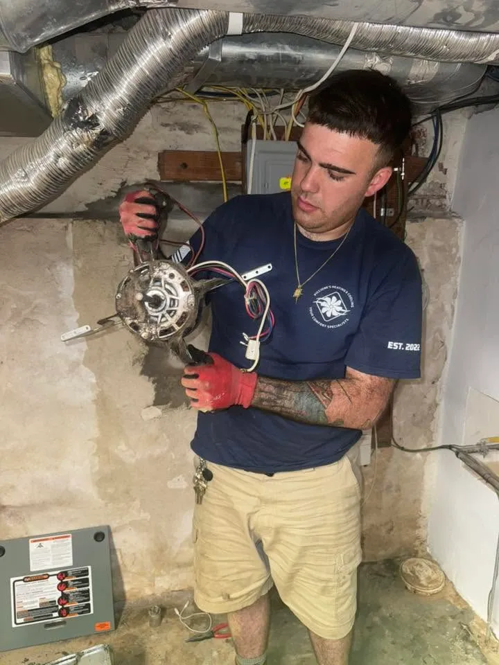 Vic Piccione of Piccione's Heating & Cooling repairing a blower motor in a South Philadelphia basement